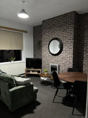 a living room with a table and a brick wall at Farm Street House by Sapphire Properties -Near to BAE Systems in Barrow