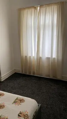 a bedroom with a bed and a window with curtains at My House in Bolton
