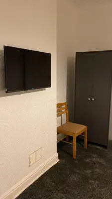 a room with a chair and a flat screen tv on a wall at My House in Bolton