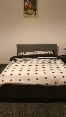 a bed with a black and white comforter in a bedroom at My House in Bolton