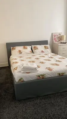 a bed with white sheets and pillows on it at My House in Bolton