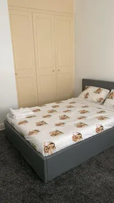 a bed with a white comforter with flowers on it at My House in Bolton
