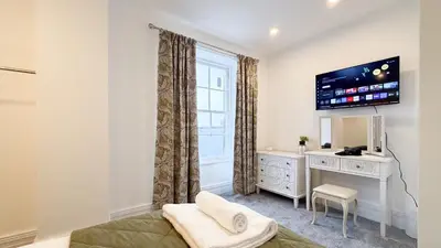 a bedroom with a bed and a dresser and a window at Hamilton Square Gardens Apartments by Rework Accommodation in Birkenhead