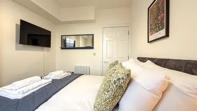 a bedroom with a white bed and a television at Hamilton Square Gardens Apartments by Rework Accommodation in Birkenhead