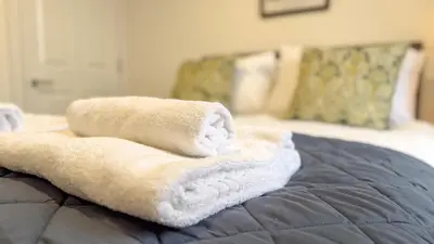 a pile of towels sitting on top of a bed at Hamilton Square Gardens Apartments by Rework Accommodation in Birkenhead