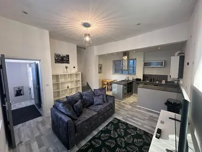 a living room with a couch and a kitchen at Modern Central Flat - Business and Leisure Stays in Preston