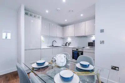 a white kitchen with a glass table and chairs at Luxury River Mersey Retreat in Central Liverpool in Liverpool