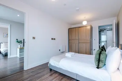 a bedroom with a white bed and a wooden cabinet at Luxury River Mersey Retreat in Central Liverpool in Liverpool
