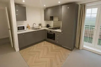 a kitchen with gray cabinets and a large window at Modern One Bedroom Flat near Anfield Stadium with Parking in Liverpool