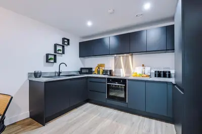 a kitchen with black cabinets and a sink at Prestige Point Stylish City Apartment In Liverpool in Liverpool