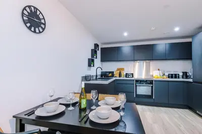 a kitchen with a table and a clock on the wall at Prestige Point Stylish City Apartment In Liverpool in Liverpool