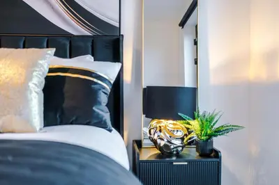 a bedroom with a black and white bed with a plant on a night stand at Prestige Point Stylish City Apartment In Liverpool in Liverpool