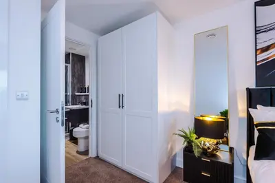 a bedroom with white cabinets and a bed and a bathroom at Prestige Point Stylish City Apartment In Liverpool in Liverpool