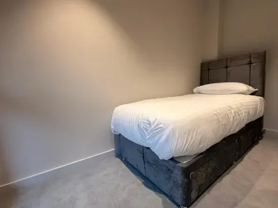 a small bedroom with a bed with white sheets at The Barn in Courtyard in Ulverston