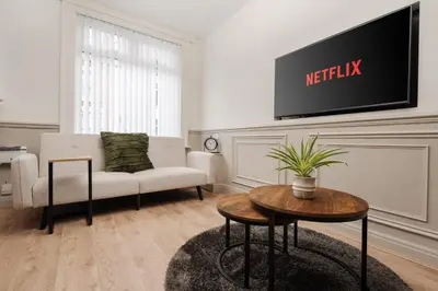 a living room with a couch and a tv on the wall at Anfield 3 Mins Superfast WiFi Washer SofaBed in Liverpool