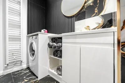 a white laundry room with a washer and dryer at Anfield 3 Mins Superfast WiFi Washer SofaBed in Liverpool