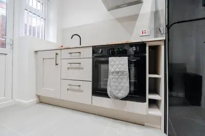 a kitchen with an oven with a towel hanging on it at Anfield 3 Mins Superfast WiFi Washer SofaBed in Liverpool