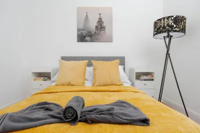 a bedroom with a bed with yellow sheets and a lamp at Anfield 3 Mins Superfast WiFi Washer SofaBed in Liverpool