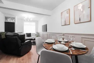 a living room with a table and a chair at Anfield 3 Mins Superfast WiFi Washer SofaBed in Liverpool