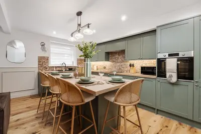 a kitchen with green cabinets and a table with chairs at Dee Street Retreat - A coastal escape in St Annes in Lytham St Annes