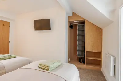 a white bedroom with two beds and a closet at Dee Street Retreat - A coastal escape in St Annes in Lytham St Annes