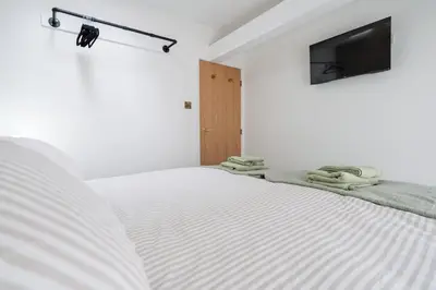a white bedroom with a bed and a tv at Dee Street Retreat - A coastal escape in St Annes in Lytham St Annes