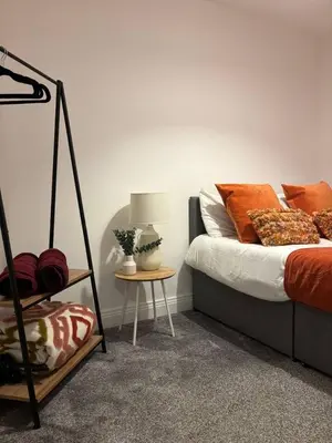 a bedroom with a bed with orange pillows and a table at Cozy 3-BR | Home in Merseyside | Free Parking in Bidston