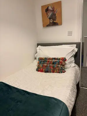 a bed with a colorful pillow on top of it at Cozy 3-BR | Home in Merseyside | Free Parking in Bidston