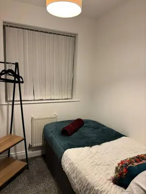 a bedroom with a bed with a red pillow on it at Cozy 3-BR | Home in Merseyside | Free Parking in Bidston