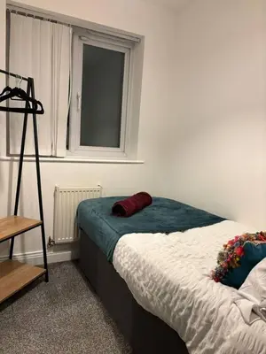 a bed in a room with a window and a bed sidx sidx sidx at Cozy 3-BR | Home in Merseyside | Free Parking in Bidston
