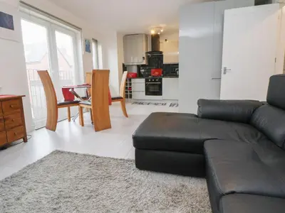a living room with a black leather couch and a kitchen at Flat 12 in Wallasey