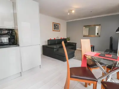 a living room with a black couch and a table at Flat 12 in Wallasey