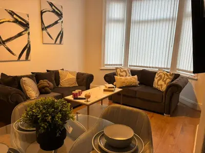 a living room with a couch and a table at Luxe 4-BR Birkenhead Home | Free Parking & Wi-Fi in Bidston