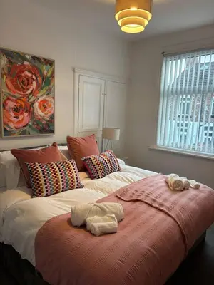 a bedroom with a large bed with towels on it at Luxe 4-BR Birkenhead Home | Free Parking & Wi-Fi in Bidston