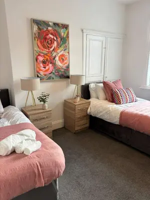 a bedroom with two beds and a painting on the wall at Luxe 4-BR Birkenhead Home | Free Parking & Wi-Fi in Bidston