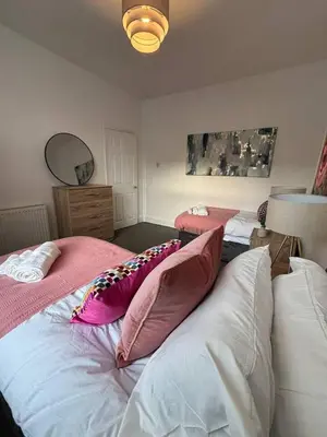 a bedroom with two beds with pink and white pillows at Luxe 4-BR Birkenhead Home | Free Parking & Wi-Fi in Bidston