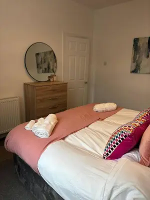 a bedroom with two beds and a dresser and a mirror at Luxe 4-BR Birkenhead Home | Free Parking & Wi-Fi in Bidston