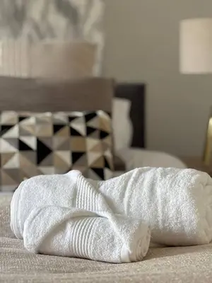 a white towel sitting on top of a bed at Luxe 4-BR Birkenhead Home | Free Parking & Wi-Fi in Bidston