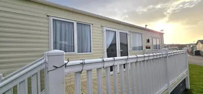 a white fence next to a house with windows at CJ's Happy Place in Heysham