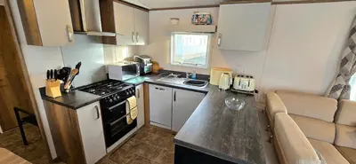a small kitchen with a stove and a couch at CJ's Happy Place in Heysham