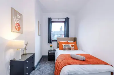 a bedroom with a bed with an orange blanket at 3-BR Home in Wigan | Free Wi-Fi | Comfortable Stay in Ince-in-Makerfield