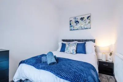 a bedroom with a bed with a blue blanket at 3-BR Home in Wigan | Free Wi-Fi | Comfortable Stay in Ince-in-Makerfield