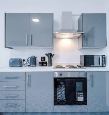a kitchen with white cabinets and a stove top oven at 3-BR Home in Wigan | Free Wi-Fi | Comfortable Stay in Ince-in-Makerfield