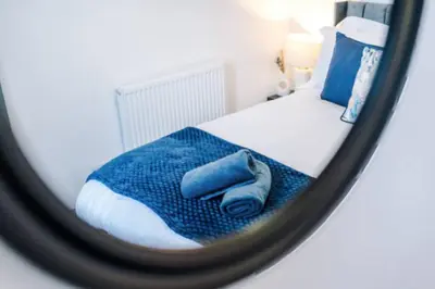 a mirror reflection of a bed with a blue blanket at 3-BR Home in Wigan | Free Wi-Fi | Comfortable Stay in Ince-in-Makerfield
