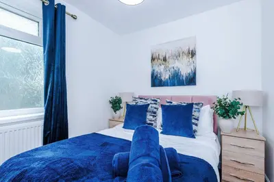 a bedroom with a blue bed with blue pillows at Comfy 3-BR Wirral Home | Free Parking & Wi-Fi in Bidston