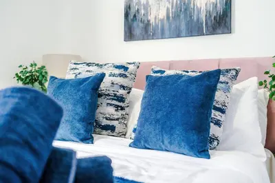 a white couch with blue pillows on it at Comfy 3-BR Wirral Home | Free Parking & Wi-Fi in Bidston