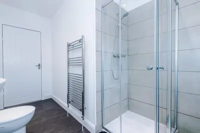 a white bathroom with a shower and a toilet at Comfy 3-BR Wirral Home | Free Parking & Wi-Fi in Bidston
