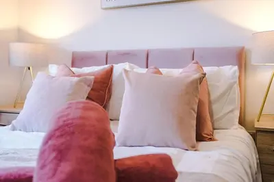 a bed with a bunch of pillows on it at Comfy 3-BR Wirral Home | Free Parking & Wi-Fi in Bidston