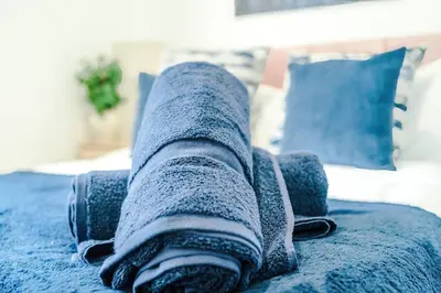 a blue blanket laying on top of a bed at Comfy 3-BR Wirral Home | Free Parking & Wi-Fi in Bidston
