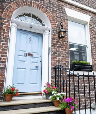 a blue door on a brick house with potted plants at Cosy Georgian Quarter Apartment - Sleeps 4 in Liverpool